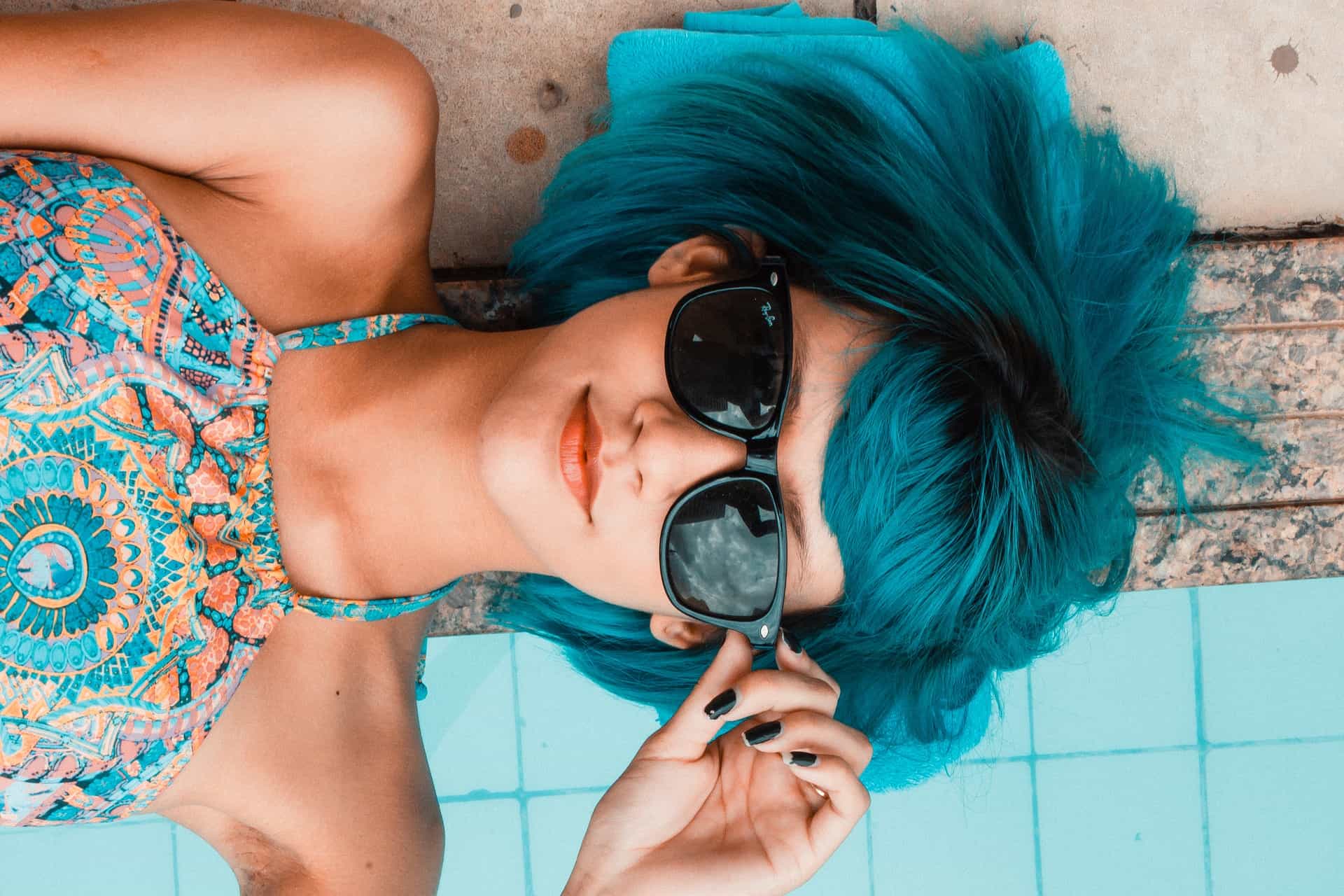 Close up of blue hair girl laying on the edge of pool