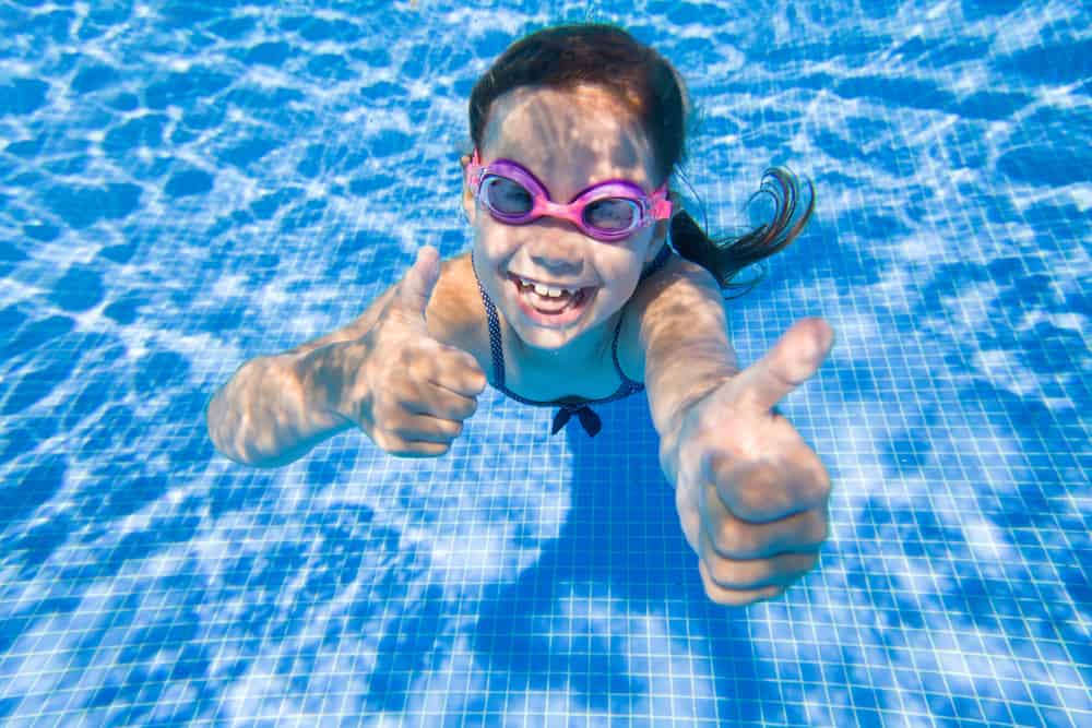 Cheerful little girl playing under water in pool