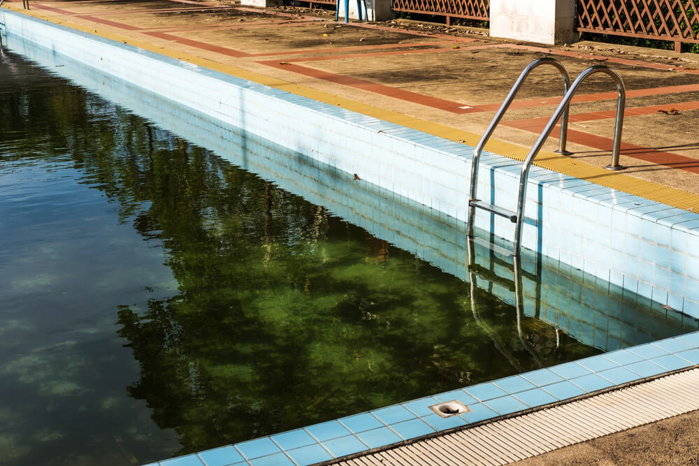 Old abandoned swimming pool with dirty water